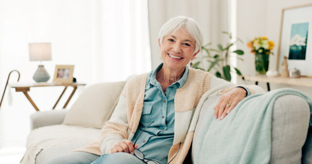 Happy senior woman sitting on sofa in one of our senior apartments in Mandeville